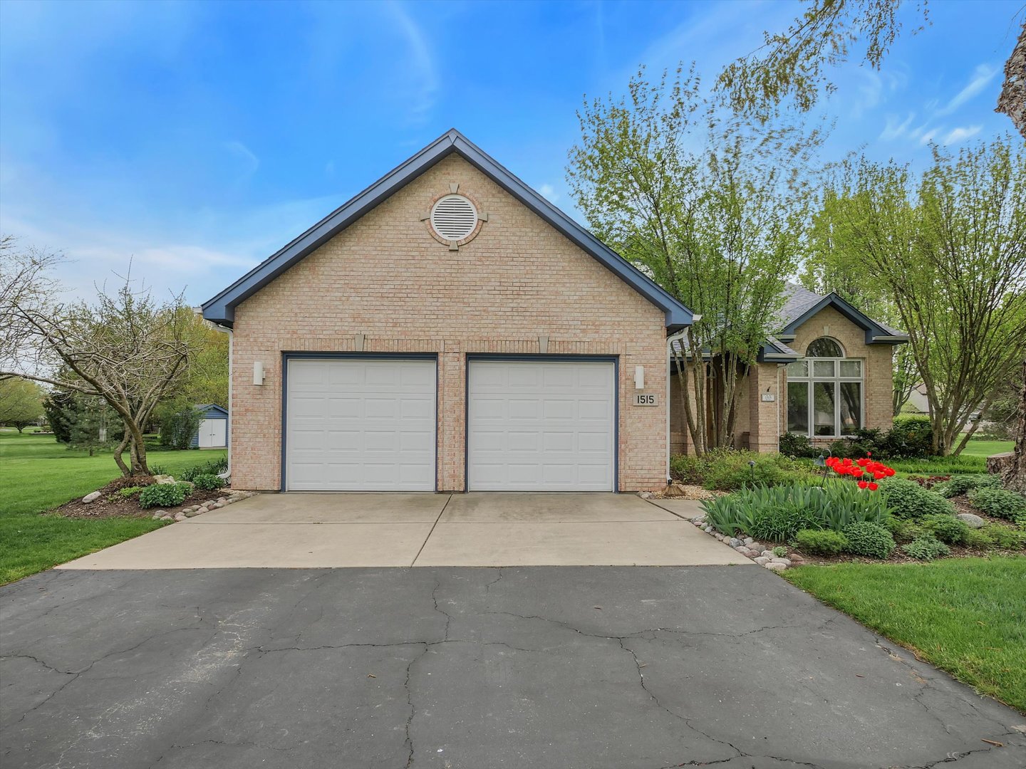 front view of house with a yard and trees all around
