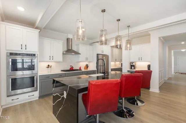 a kitchen with stainless steel appliances kitchen island granite countertop a dining table chairs and a refrigerator