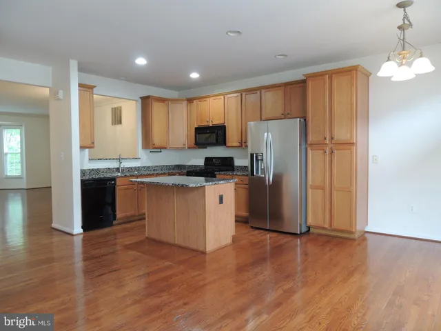 a kitchen with granite countertop wooden floors stainless steel appliances and a counter space