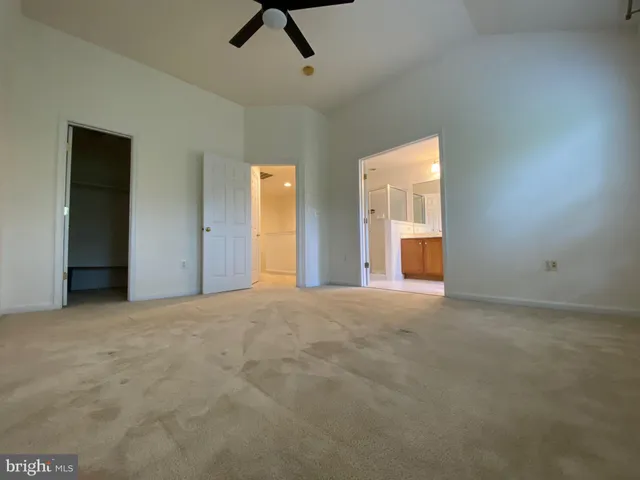 a view of an empty room with chandelier fan and windows