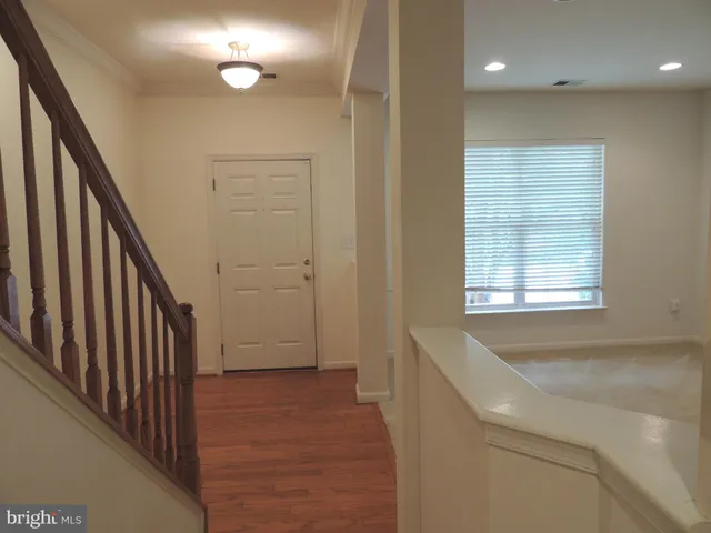 a view of a hallway with wooden floor and staircase
