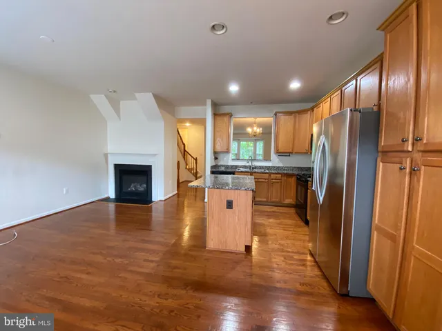 a kitchen with stainless steel appliances granite countertop a refrigerator a oven a sink with wooden floors