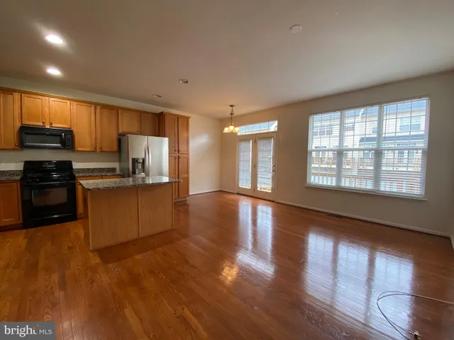 a kitchen with stainless steel appliances granite countertop a stove a sink a refrigerator white cabinets and wooden floor