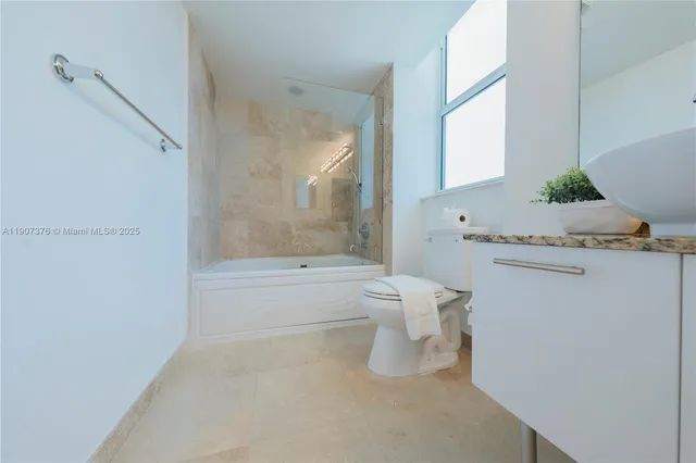 a bathroom with a granite countertop sink mirror and a toilet
