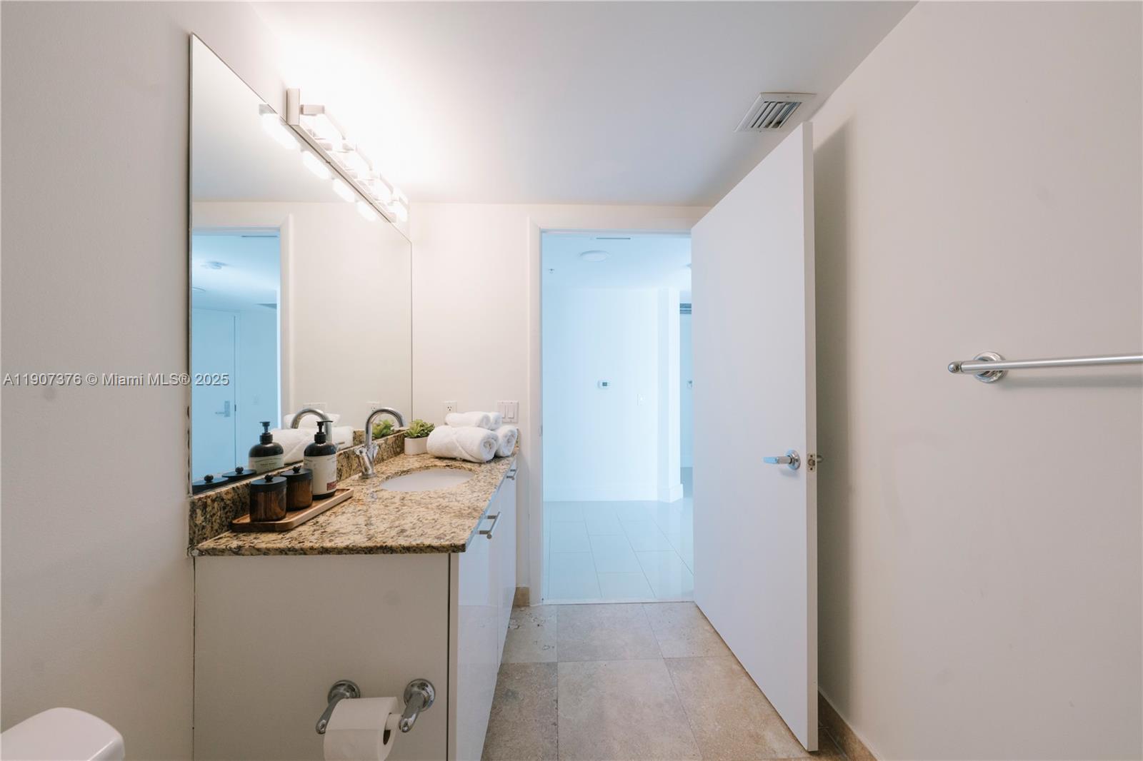 41 Southeast 5th Street, Unit 1217 Miami, FL 33131 - Photo 9 of 24 a bathroom with a granite countertop sink and a mirror