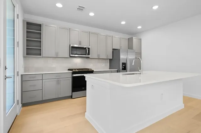 a kitchen with kitchen island a sink stainless steel appliances and cabinets