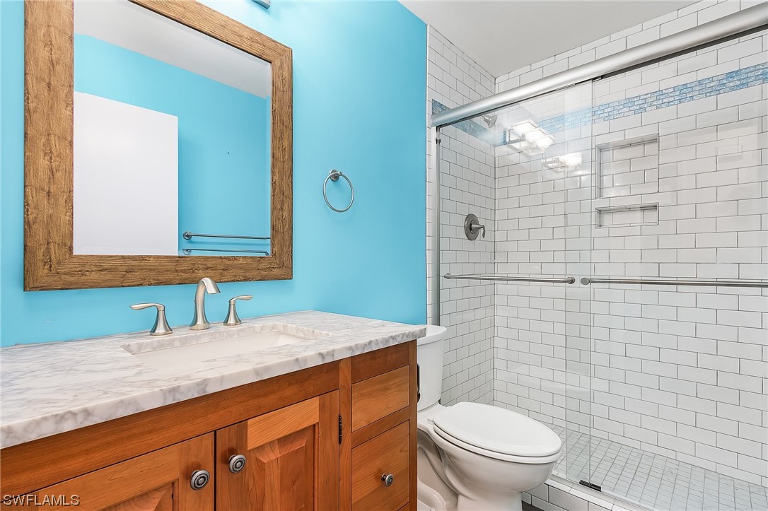 13673 Hampton Road Bokeelia, FL 33922 - Photo 17 of 28 a bathroom with a granite countertop toilet sink and mirror