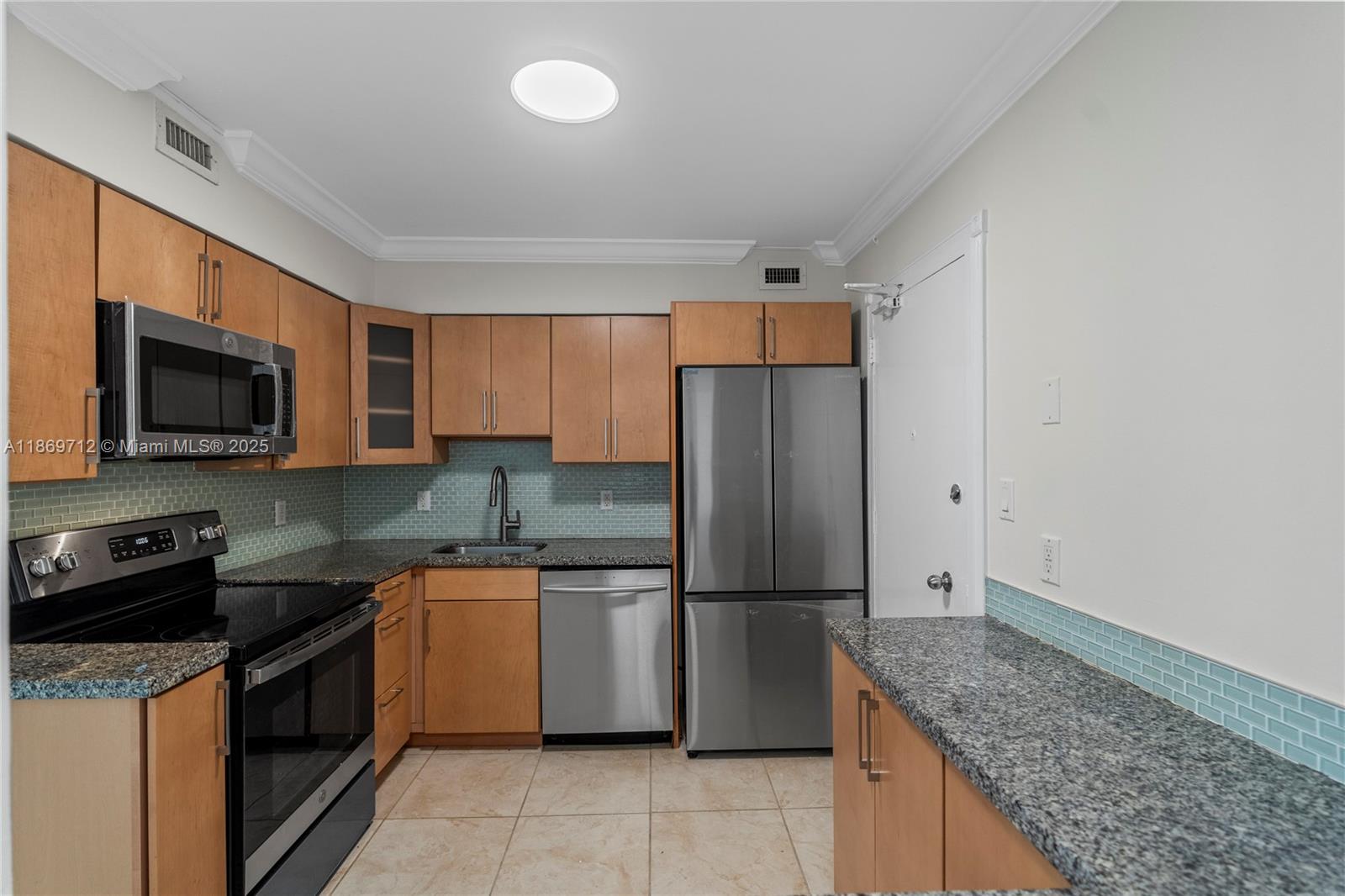 5161 Collins Avenue, Unit 701 Miami Beach, FL 33140 - Photo 13 of 47 a kitchen with a sink a refrigerator a microwave and cabinets
