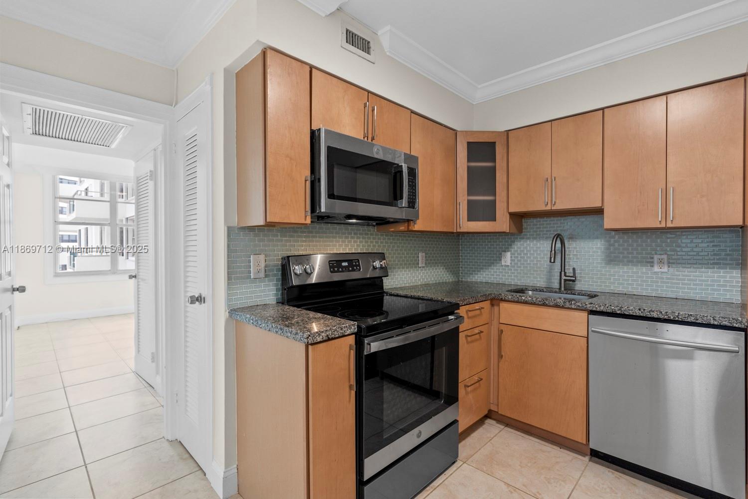 5161 Collins Avenue, Unit 701 Miami Beach, FL 33140 - Photo 14 of 47 a kitchen with stainless steel appliances granite countertop a stove a sink and a microwave