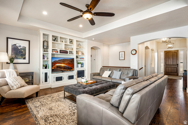 2311 South 1340 West St. George, UT 84770 - Photo 12 of 56 Living area featuring a raised ceiling, built in shelves, dark wood-style flooring, a ceiling fan, and a fireplace