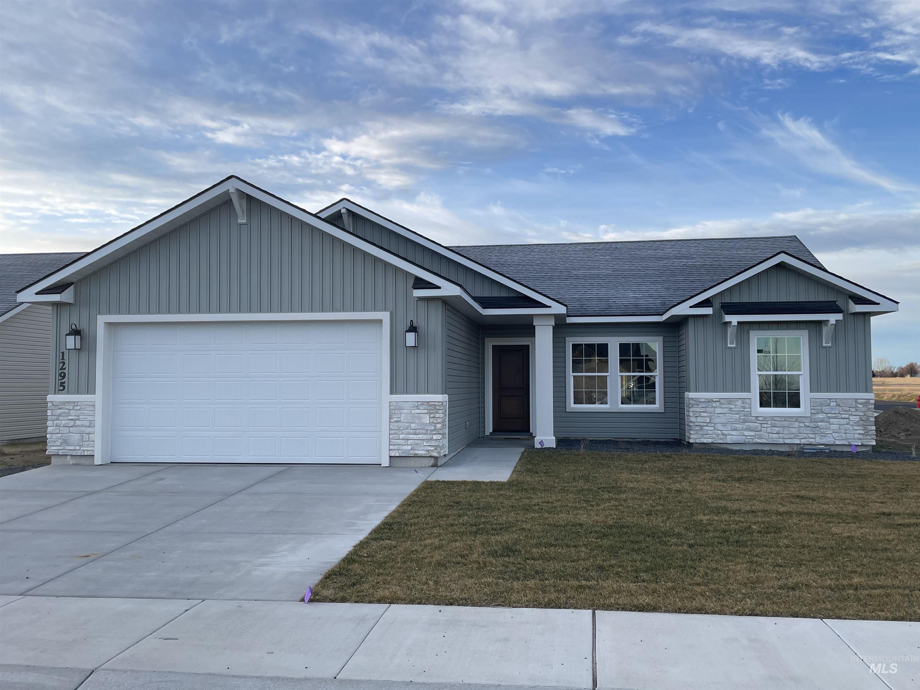 View of front of house featuring stone siding, a front lawn, board and batten siding, and a garage