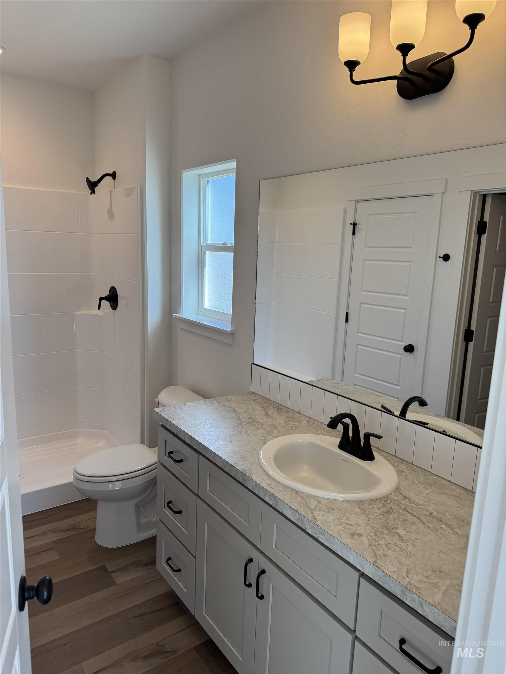 1295 Starlight Loop Twin Falls, ID 83301 - Photo 6 of 11 Full bath with vanity, dark wood finished floors, a shower stall, and a chandelier