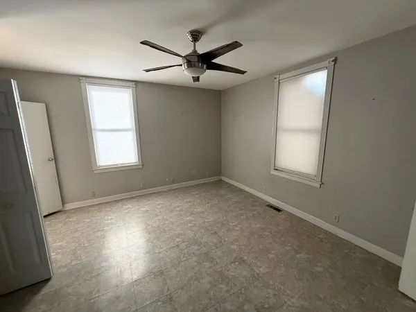 an empty room with windows and fan