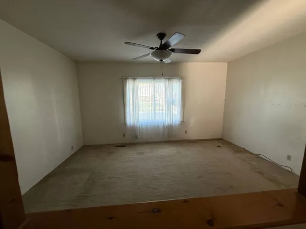 an empty room with a window and a fan