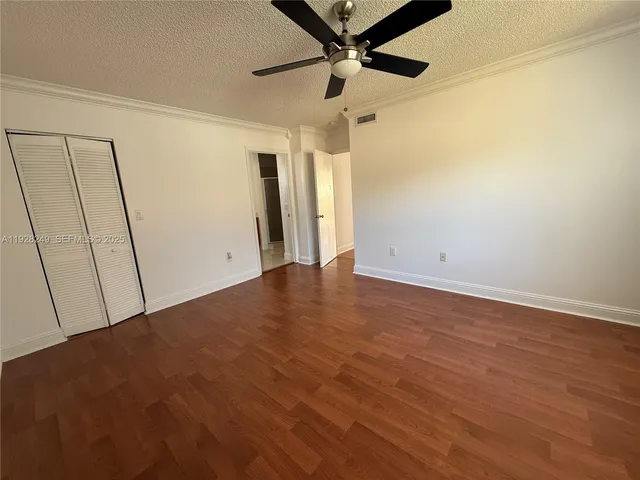 an empty room with wooden floor fan and windows