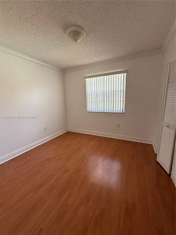 a view of an empty room with wooden floor and window