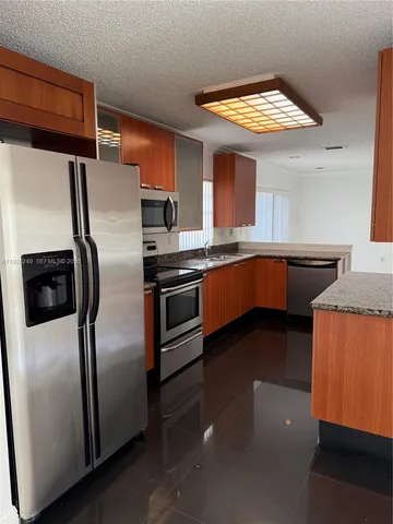 a kitchen with stainless steel appliances granite countertop a refrigerator a sink a stove and island
