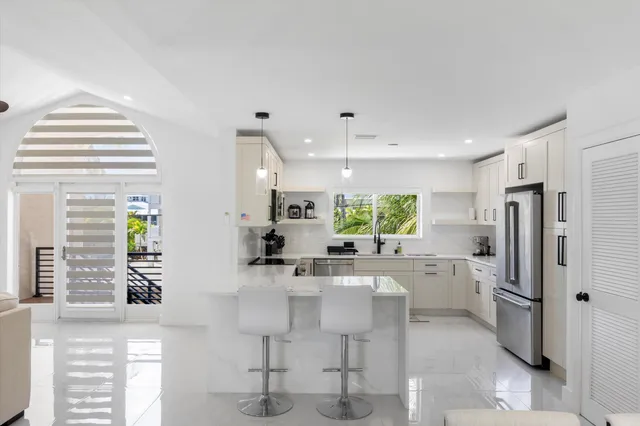 a kitchen with stainless steel appliances a refrigerator a sink a stove and white cabinets