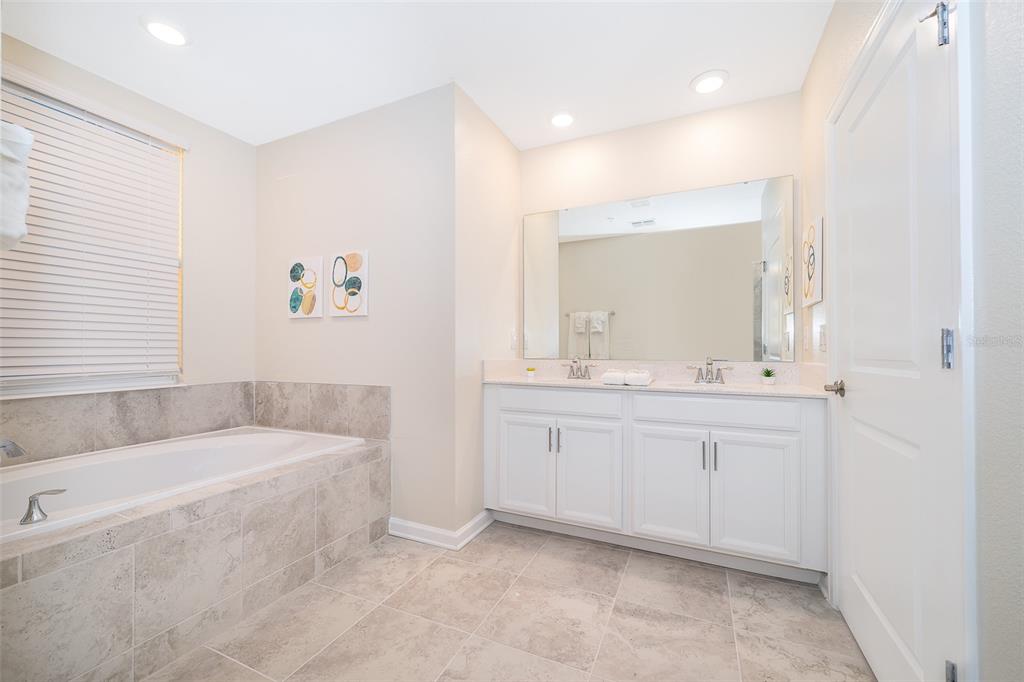 817 Ocean Course Avenue Davenport, FL 33896 - Photo 15 of 32 a bathroom with a tub a sink and mirror