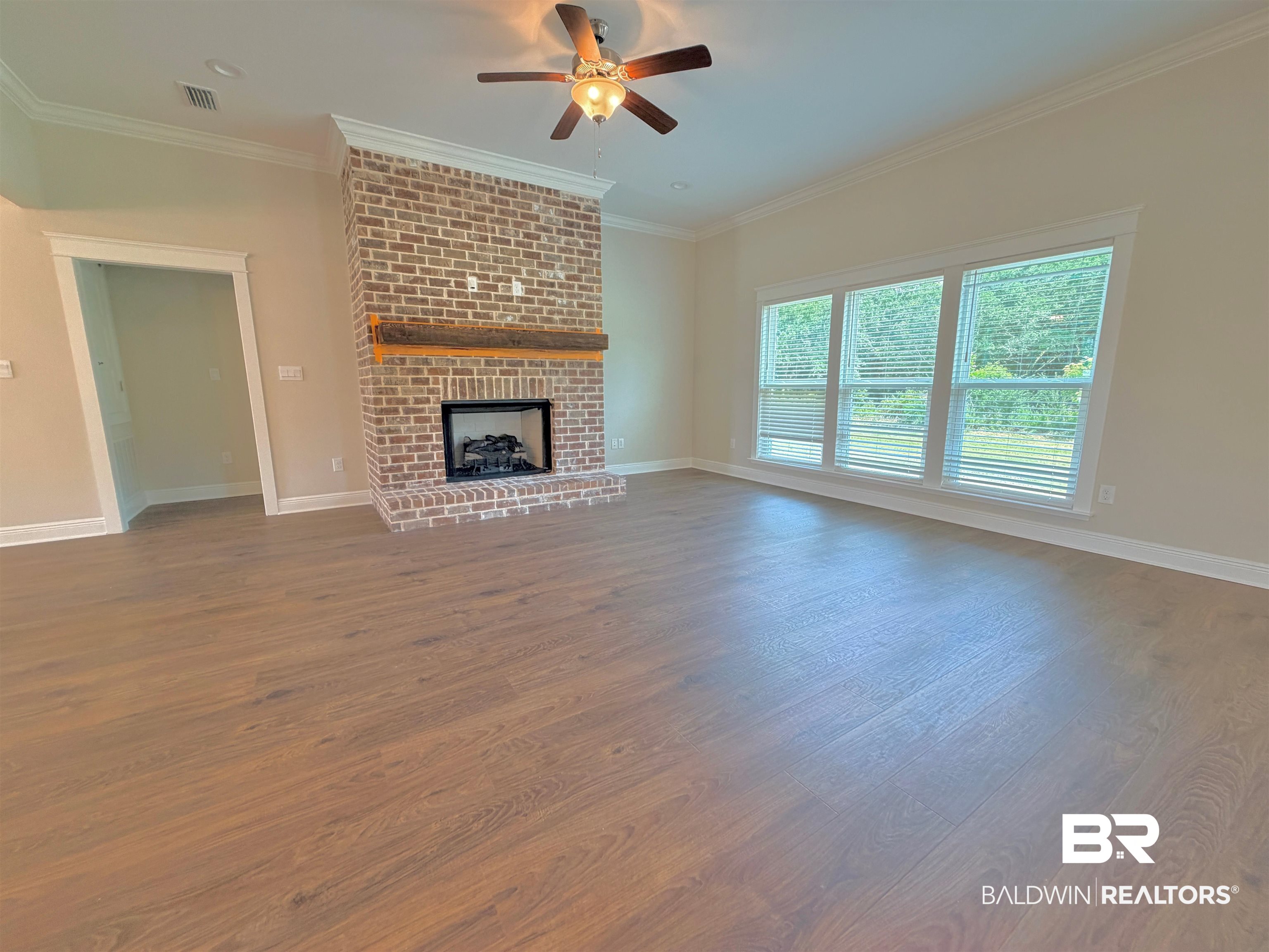 318 Morning Mist Way Fairhope, AL 36532 - Photo 3 of 20 Spacious interior featuring wood-finish flooring, a prominent brick fireplace with a wood mantel, and multiple windows providing natural illumination