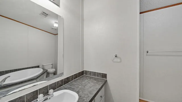 a bathroom with a granite countertop sink mirror vanity and toilet