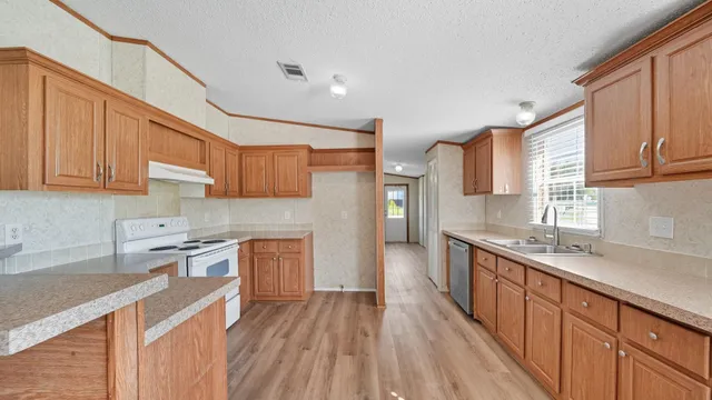 a kitchen with stainless steel appliances granite countertop wooden cabinets a sink and dishwasher a stove with wooden floor