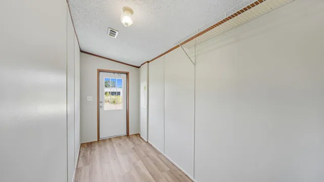a view of an empty room with closet and a window