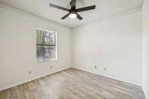 an empty room with a window and a ceiling fan