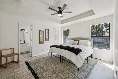 a bedroom with a bed and dresser with wooden floor