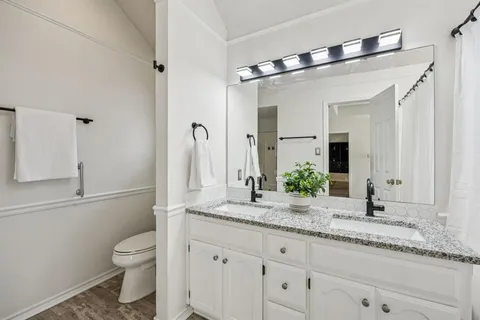 a bathroom with a granite countertop sink a toilet and shower