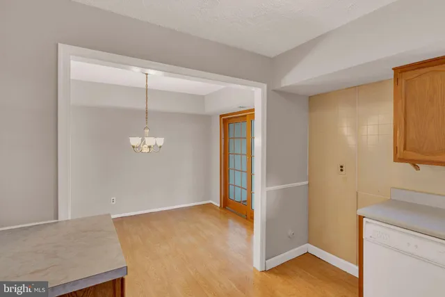 an empty room with wooden floor mirror and windows