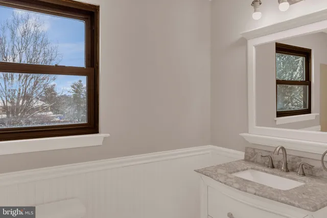 a bathroom with a granite countertop sink and a window