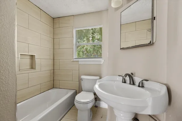 a white bath tub sitting next to a white sink and a toilet