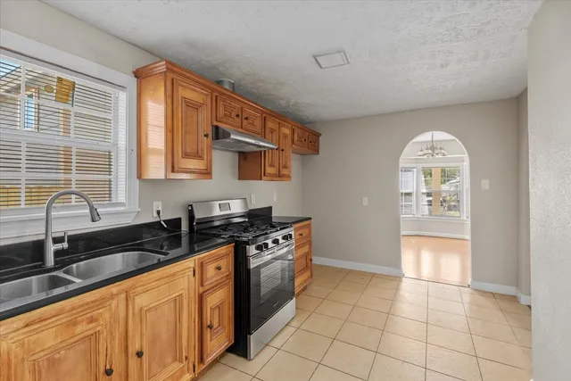 a kitchen with stainless steel appliances granite countertop a stove a sink and a microwave