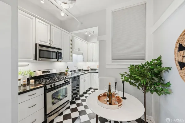 a kitchen with stainless steel appliances a sink a stove a microwave a dining table and chairs