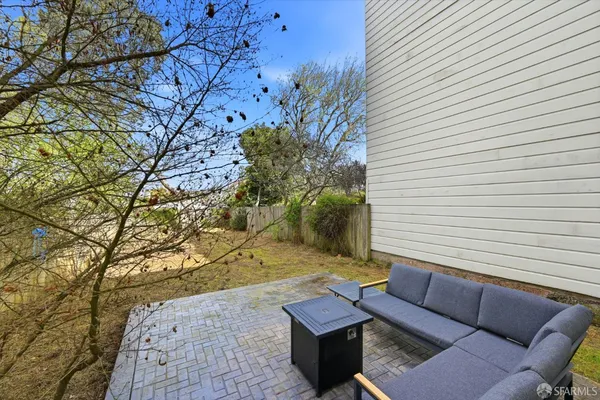 a view of a backyard with couches and a fire pit and a large tree