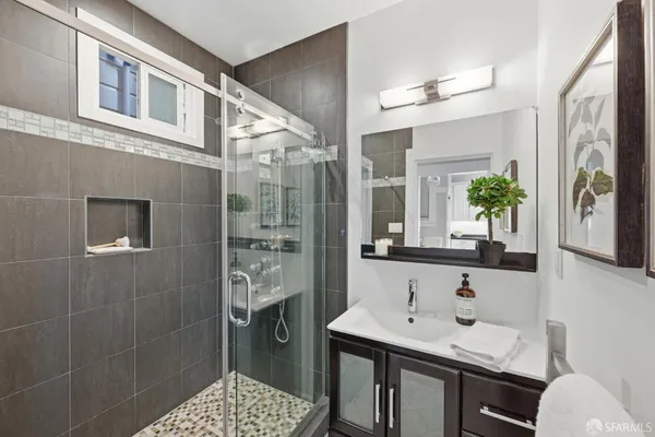 a bathroom with a granite countertop sink a toilet a mirror and shower