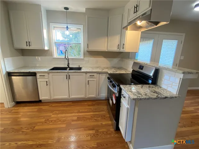 a kitchen with stainless steel appliances granite countertop a stove sink and cabinets
