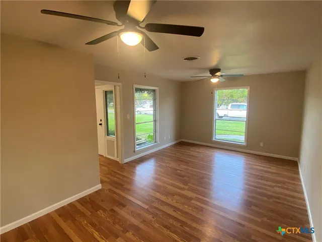 a view of an empty room with window and wooden floor