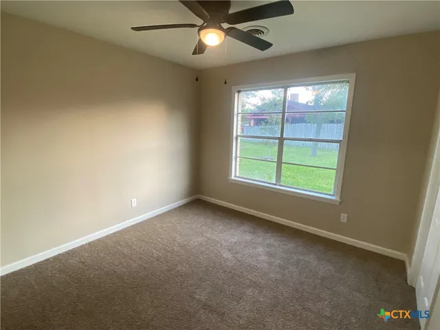 en empty room with windows and ceiling fan