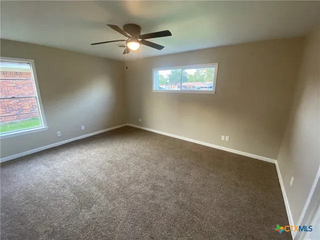 an empty room with windows and fan