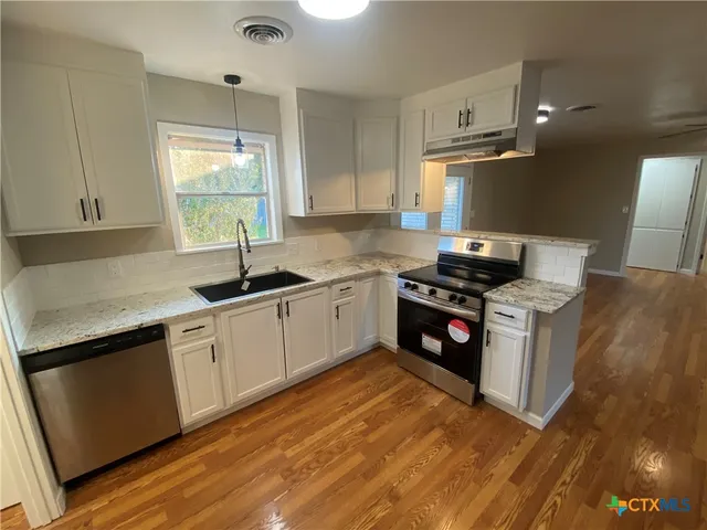 a kitchen with a sink stove top oven and cabinets