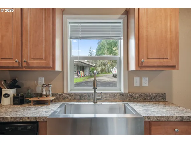 a kitchen with granite countertop a sink window and cabinets