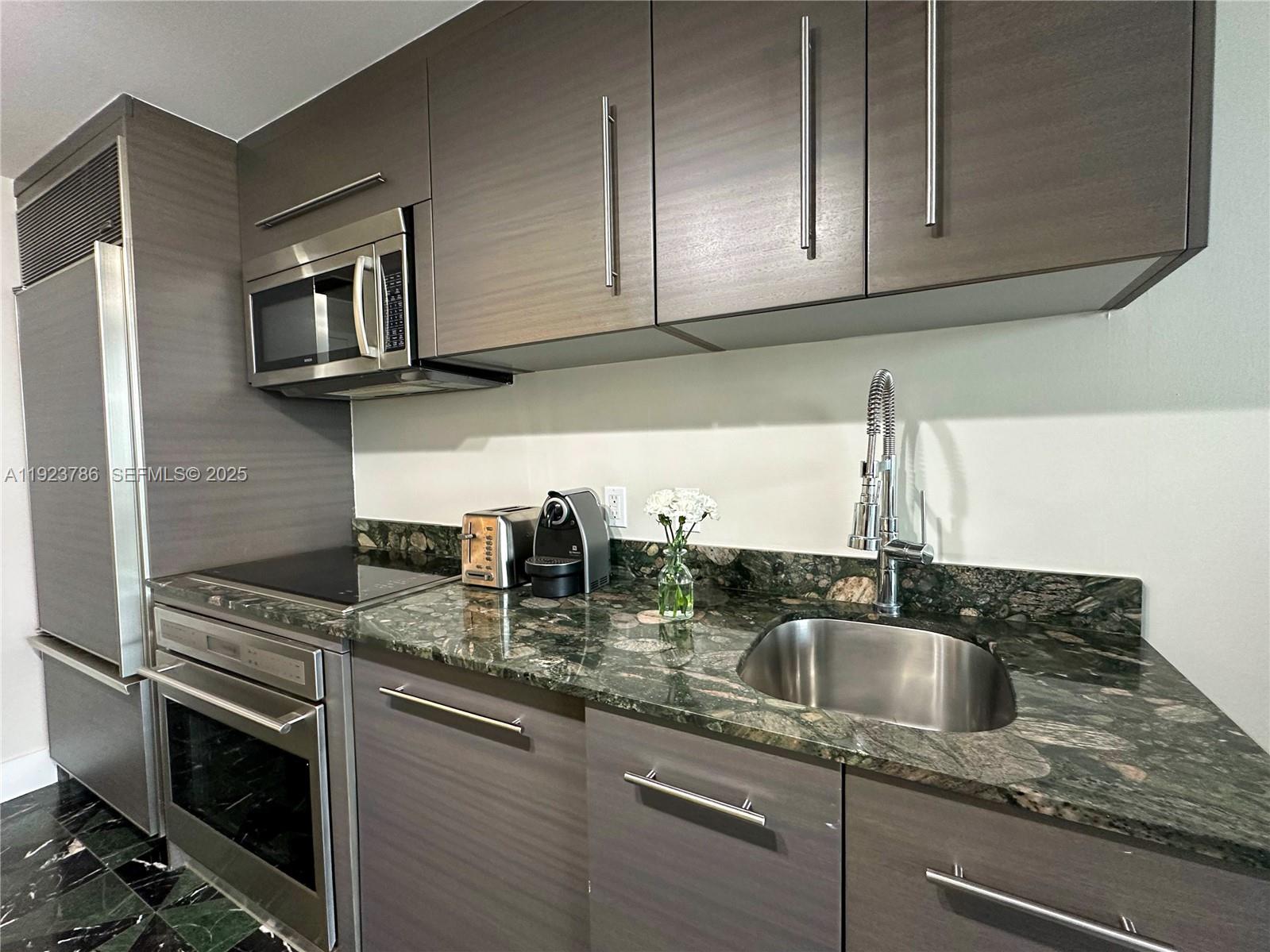 485 Brickell Avenue, Unit 4405 Miami, FL 33131 - Photo 11 of 19 a kitchen with granite countertop a sink stainless steel appliances and cabinets