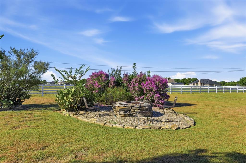 504 Casa Del Rancho Road Lorena, TX 76655 - Photo 39 of 40 Expansive backyard featuring a stone-edged fire pit area with gravel ground cover, surrounded by lush green lawn