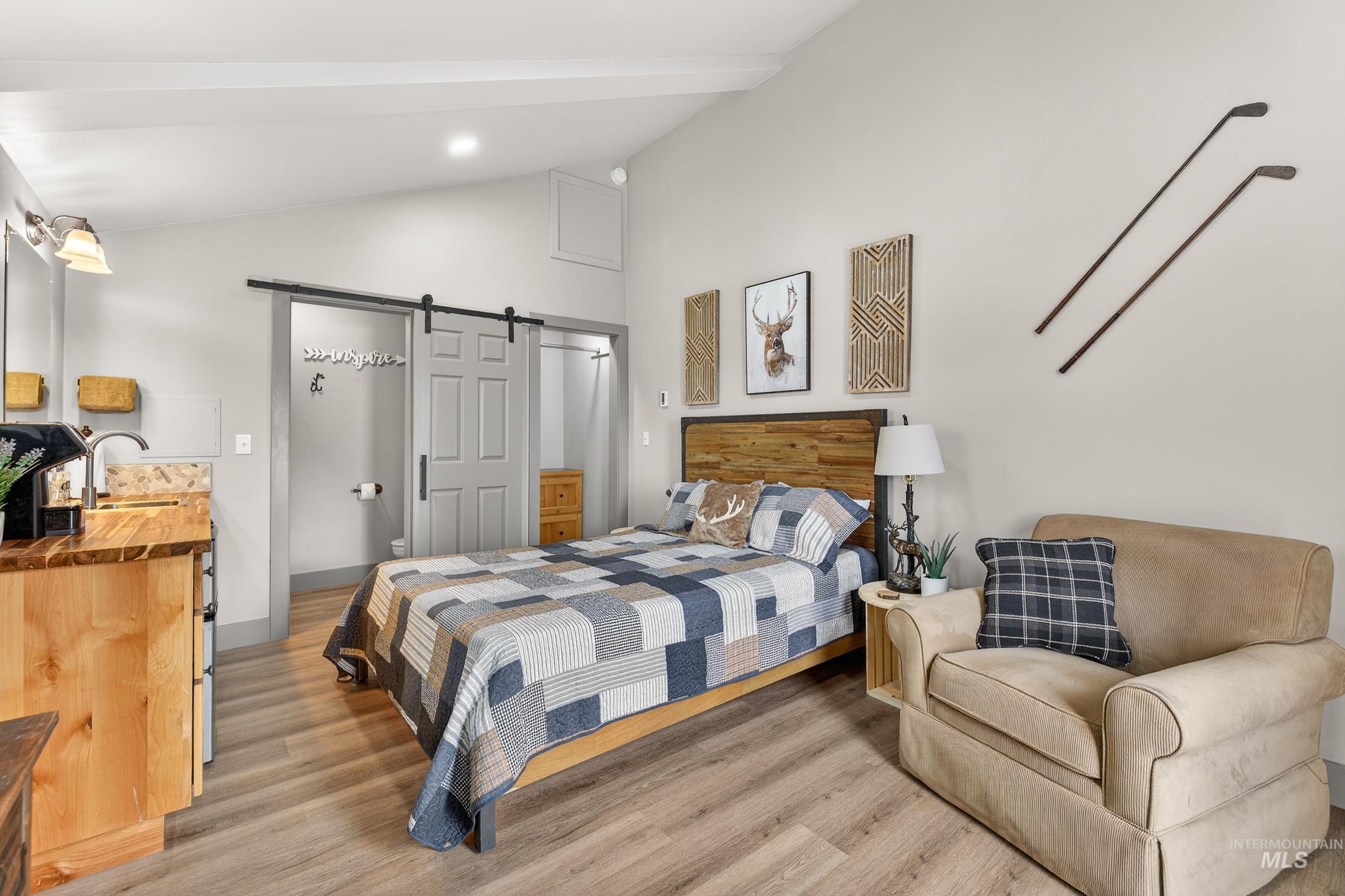 304 Samson Court, Unit 656 McCall, ID 83638 - Photo 19 of 29 Bedroom featuring a barn door, light wood finished floors, and vaulted ceiling