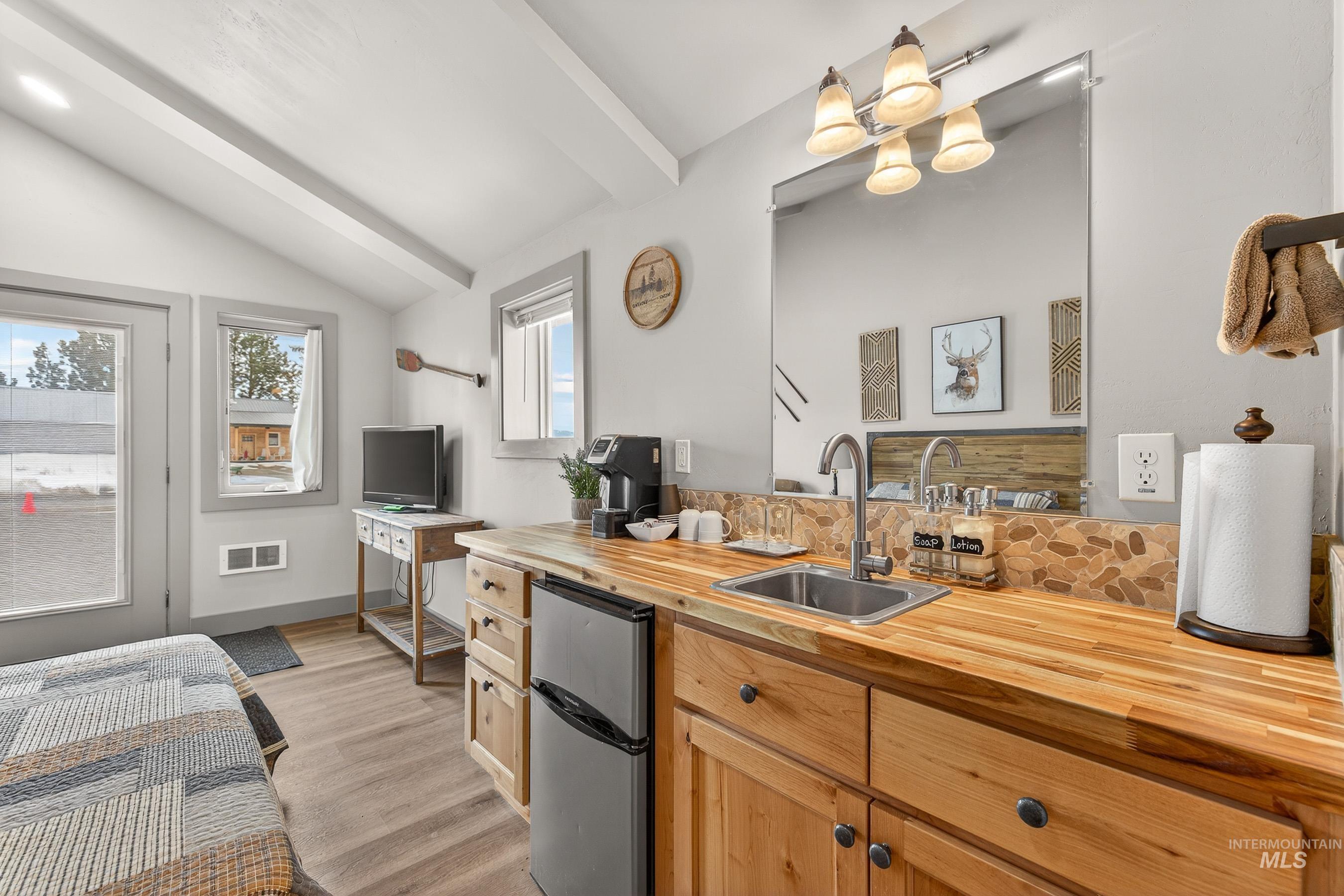 304 Samson Court, Unit 656 McCall, ID 83638 - Photo 21 of 29 Kitchen featuring butcher block countertops, freestanding refrigerator, light wood-type flooring, lofted ceiling with beams, and light wood finish cabinetry