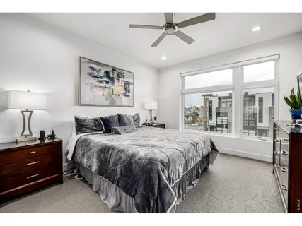 a spacious bedroom with a bed a couch and large window