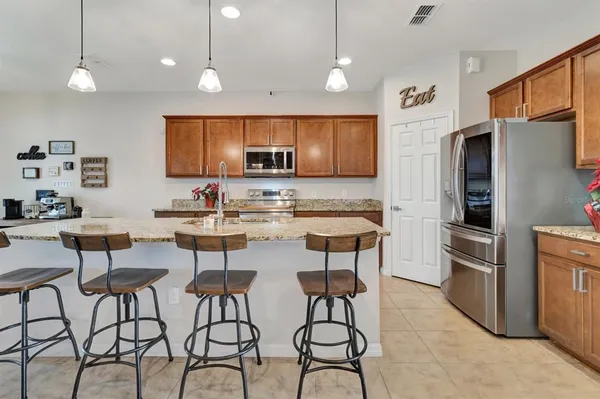 a kitchen with stainless steel appliances kitchen island granite countertop a refrigerator a stove a kitchen island with a dining table and chairs