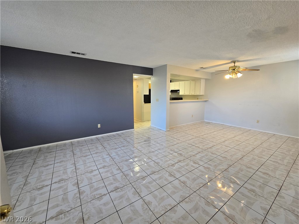 6750 Del Rey Avenue, Unit 133 Las Vegas, NV 89146 - Photo 3 of 34 A well-lit living area features easy-to-maintain tile flooring and an open flow to the kitchen.